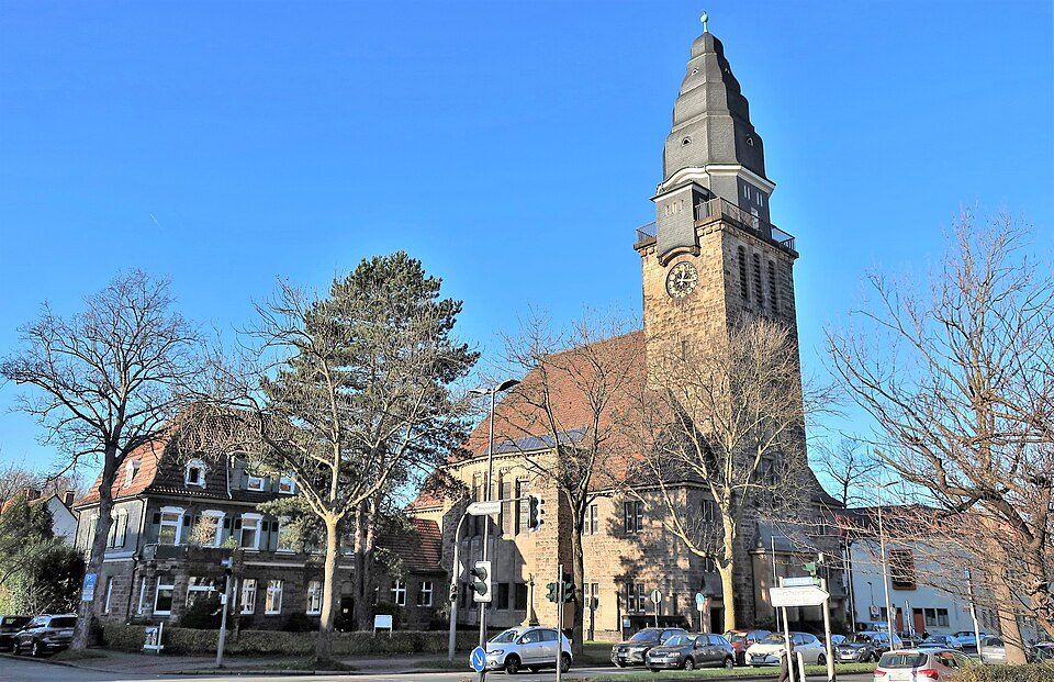 Die Melanchthonkirche mit Uhrturm an der Königsallee, daneben eine Altbauvilla, im Bochumer Ehrenfeld