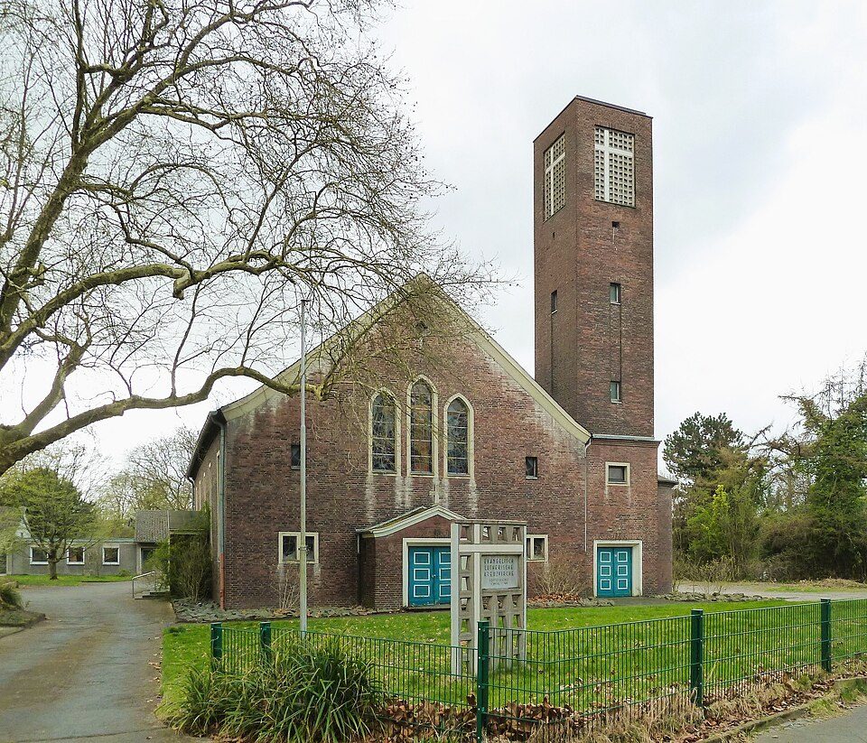 Die Kreuzkirche aus Backstein mit kantigem Glockenturm und Rasenfläche in Bochum-Hamme
