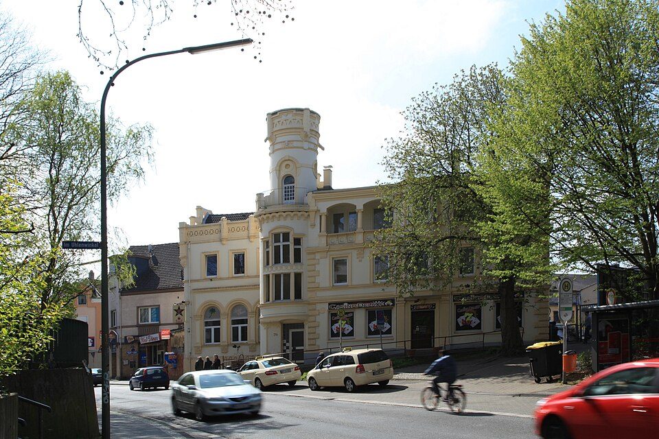 Gründerzeitliches Eckhaus mit Turmaufsatz an der Ümminger Straße in Bochum-Langendreer-Alter Bahnhof, davor Straße mit Autos und Radfahrer