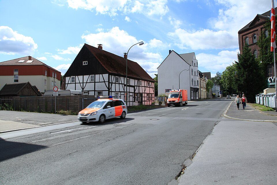 Hauptstraße in Bochum-Langendreer mit einem Fachwerkhaus, hellen Wohnhäusern und Bäumen am Straßenrand