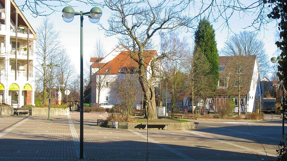 Gepflasterter Buscheyplatz in der Hustadt in Bochum-Querenburg mit Laternen, einem großen Baum und Wohnhäusern mit Satteldach