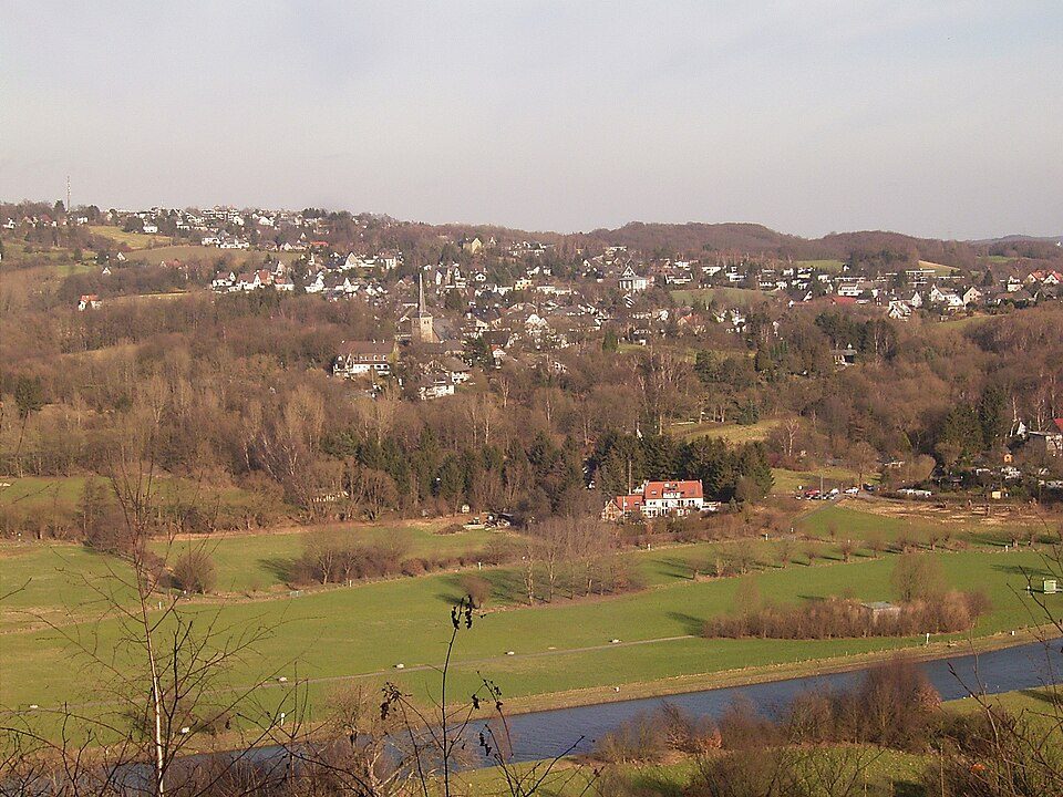 Blick über die Ruhr und die Ruhrauen auf die Wohnbebauung von Bochum-Stiepel am Hang, dazwischen Wiesen und Wald