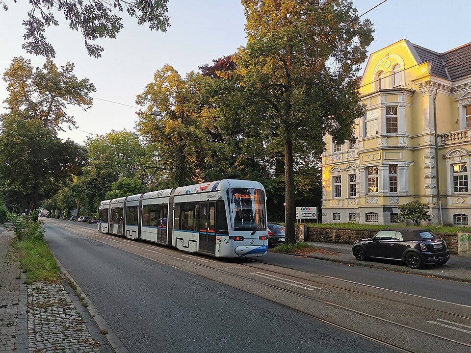 Straßenbahn auf der baumbestandenen Hattinger Straße in Bochum-Weitmar-Mitte, rechts eine gelbe Gründerzeitvilla