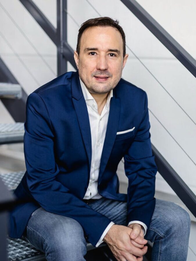 Christian Gottschling sitzt in blauem Sakko auf einer Treppe und blickt in die Kamera
